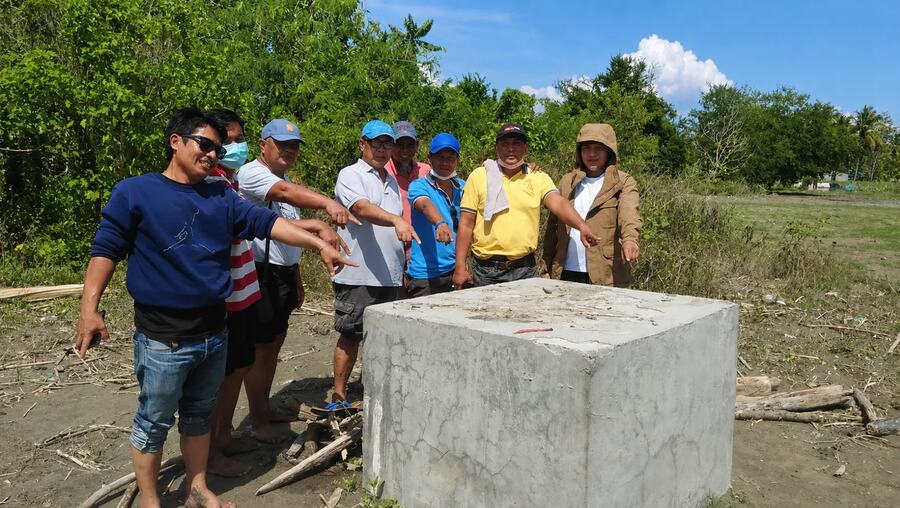 Field representatives indicating a concrete well-site structure