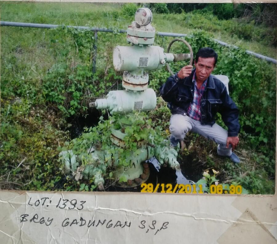Historical photograph of a legacy wellhead with a field representative, dated 29 December 2011